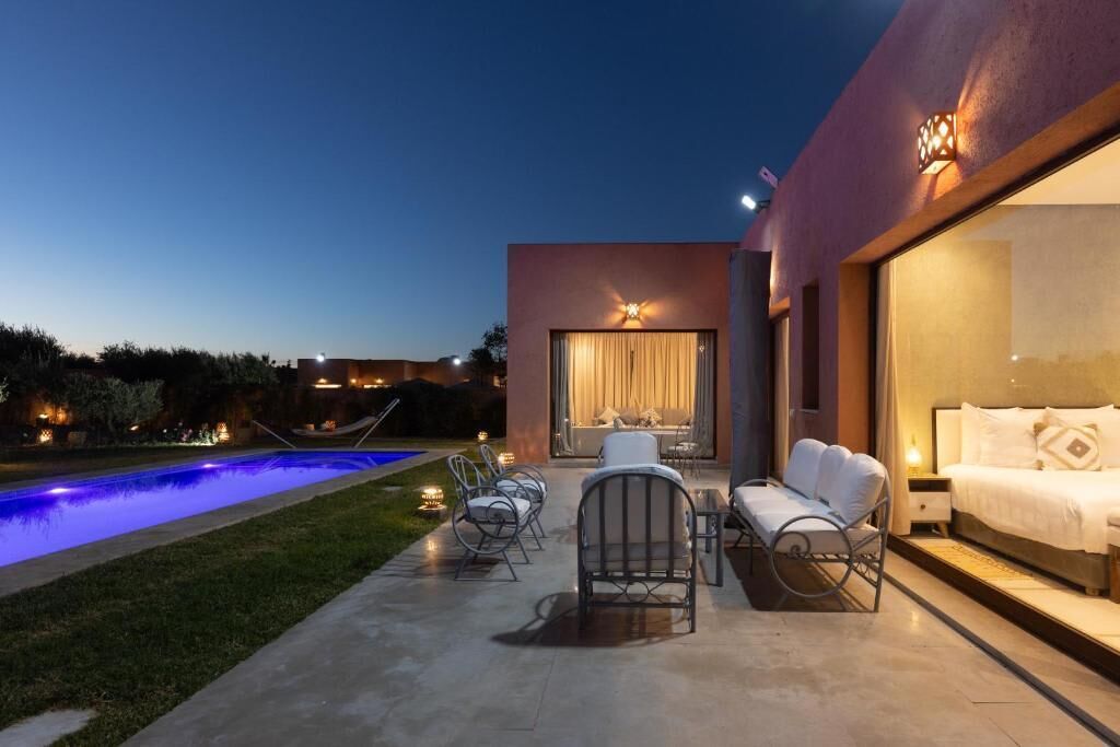 Un patio moderno al aire libre con piscina, zona de estar y un amplio ventanal con vistas a la piscina.