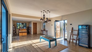 A spacious living area with a wooden floor, a blue coffee table, a chandelier, and a wine refrigerator. - Villa Bluu (Jambiani)
