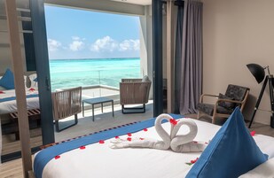 Ein Hotelzimmer mit einem Bett, einem Sessel, einem kleinen Tisch und Blick aufs Meer.