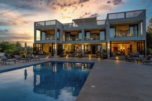Ein modernes, mehrstöckiges Gebäude mit Swimmingpool und Außenbereich mit Sitzgelegenheiten.