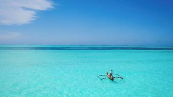 A clear turquoise sea with a small boat carrying two people.