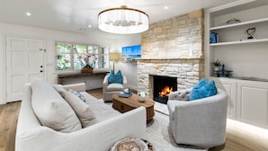 A modern living room with a stone fireplace, white furniture, and a chandelier. - 3972 DolceVita ~Beautiful Remodel, Walk Everywhere (Carmel)