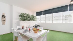A dining area with a white table, four chairs, and a green artificial grass floor. - Central Apartment - Rooftop pool (Albufeira)