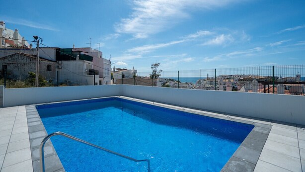 A rooftop swimming pool with a clear view of the cityscape in the background. - Central Apartment - Rooftop pool (Albufeira)