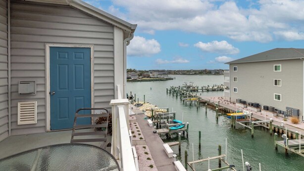 A waterfront property with a dock, boats, and a building with a blue door. - Waterfront Condo with Pool (Ocean City)