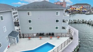 A building with a pool, a dock, and a waterfront view. - Waterfront Condo with Pool (Ocean City)