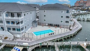 A waterfront property with a swimming pool, dock, and multiple buildings. - Waterfront Condo with Pool (Ocean City)