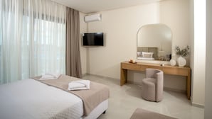 A modern hotel room with a large bed, a desk with a mirror, a chair, and a flat-screen TV.