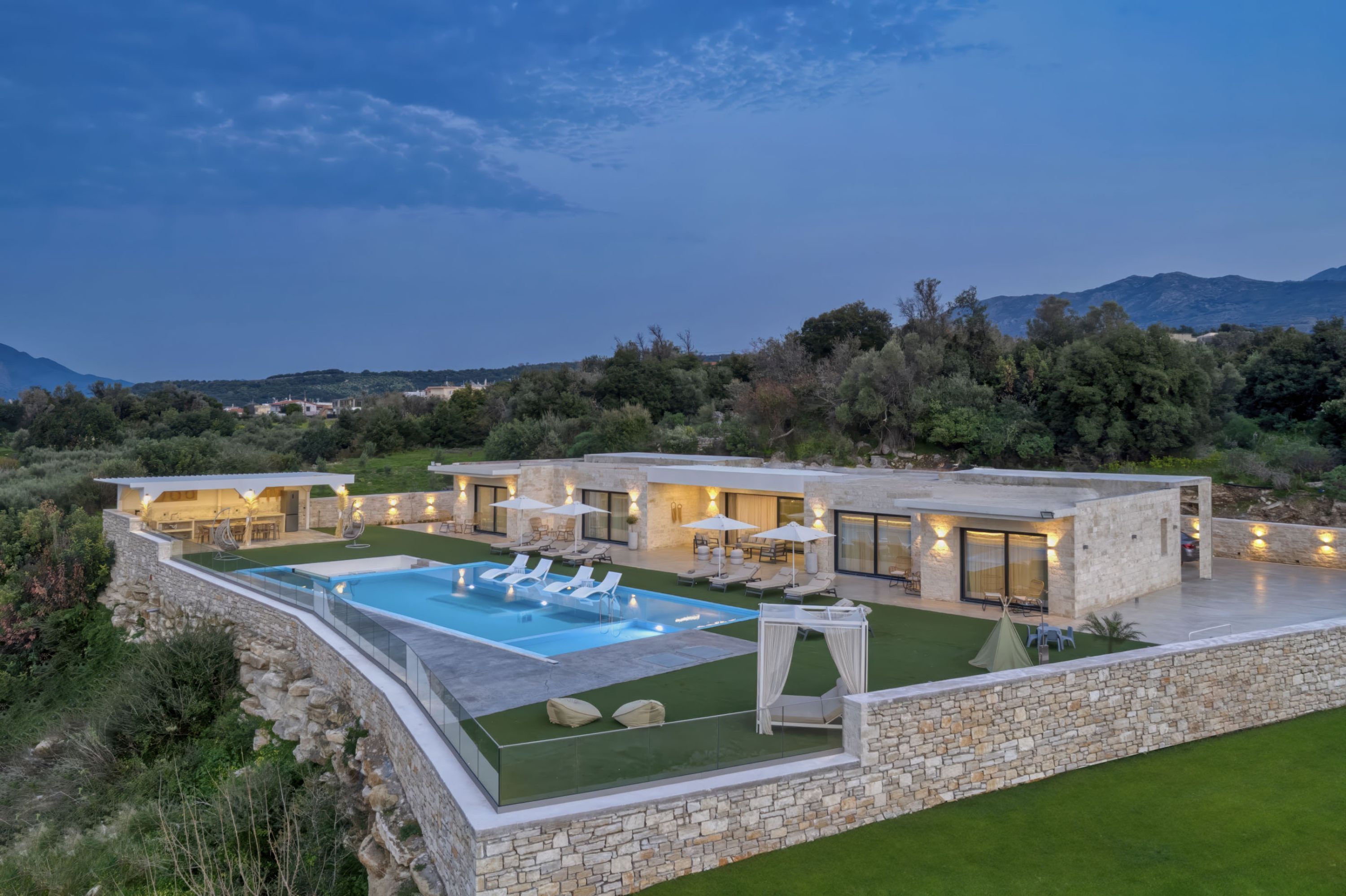 A modern house with a swimming pool, outdoor seating, and a view of the mountains.