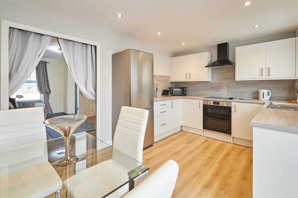 A modern kitchen with white cabinets, a stainless steel refrigerator, a microwave, and a stove.