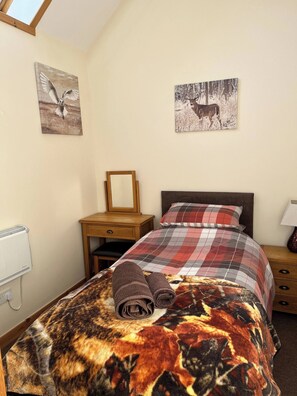 A bedroom with a bed, a nightstand, a bedside table, a radiator, and two wall-mounted pictures. - Fabulous Open Views Over Dufftown (Keith)