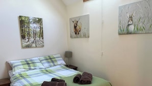 A neatly made bed with a plaid bedspread, two rolled towels, and three paintings on the wall. - Fabulous Open Views Over Dufftown (Keith)