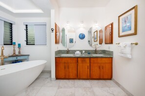 Un baño moderno con una bañera independiente, tocador de madera con lavamanos dobles y un espejo grande.