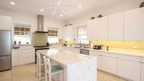 Una cocina moderna con armarios blancos, una isla central y un refrigerador de acero inoxidable.