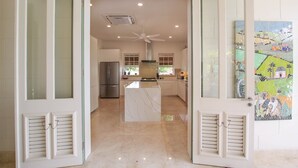 Una cocina amplia con una isla central, un refrigerador grande y un ventilador de techo.