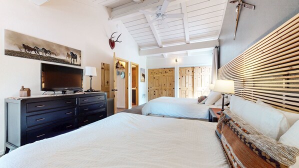 A bedroom with a bed, a dresser, a television, and a wooden headboard.