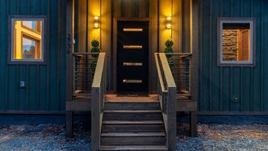 A wooden building with a dark entrance, two side lights, and a number '2736' on the wall. - Reflections 1 Bedroom Cabin (Sevierville)