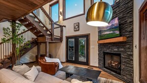 A spacious living room with a fireplace, a staircase, and a large window. - Reflections 1 Bedroom Cabin (Sevierville)
