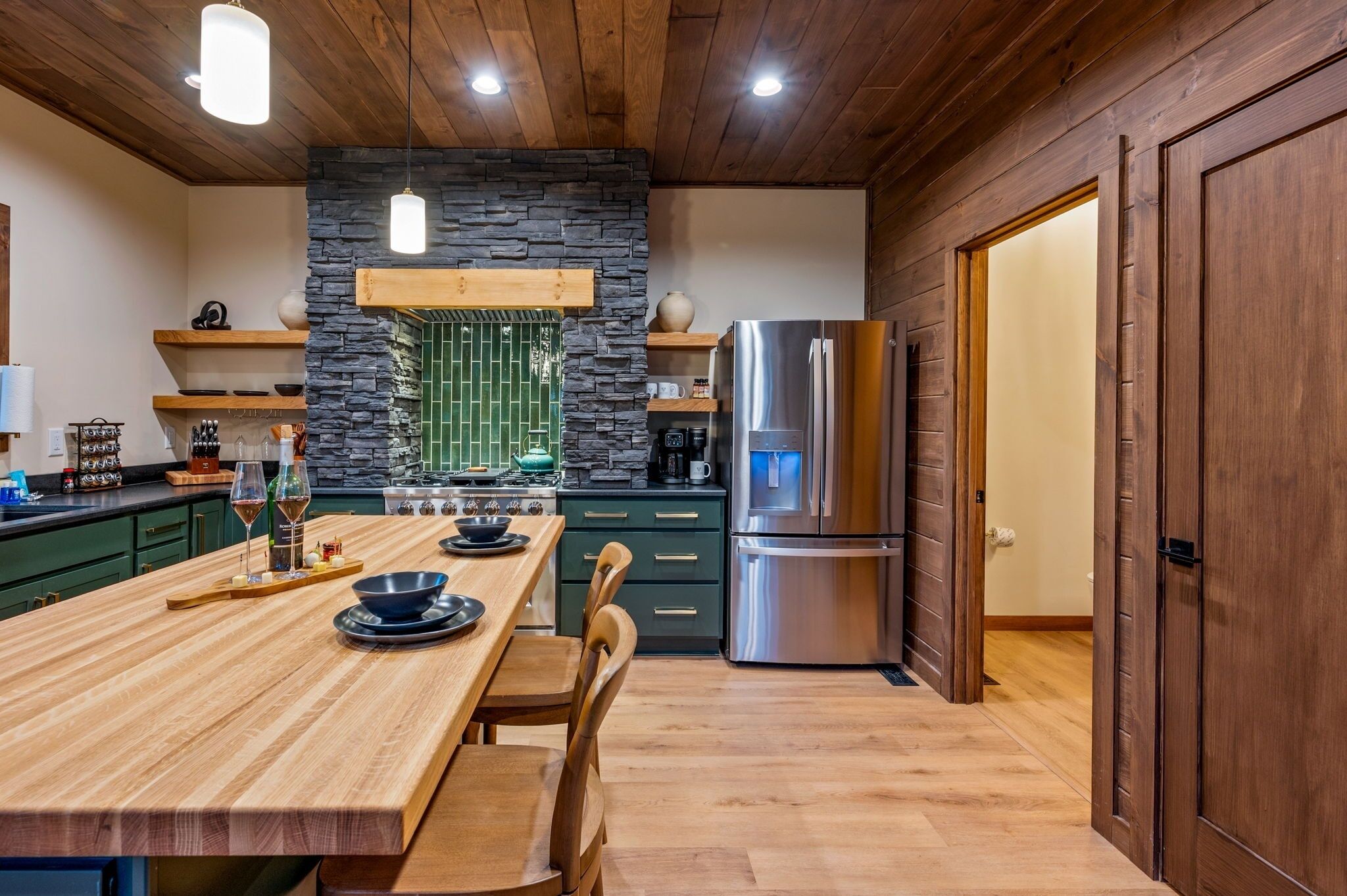 Una cocina moderna con una mesa de madera, una estufa integrada y un refrigerador de acero inoxidable.