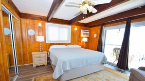 A wooden-paneled bedroom with a bed, bedside lamps, a window, and a view of the outdoors. - Village West 1 3 Bedroom Townhouse (Ocean City)