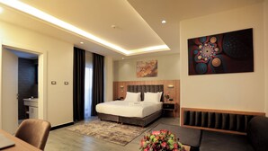 A modern hotel room with a large bed, a desk, a sofa, and a dining area. - Daylin Guest House (Addis Ababa)