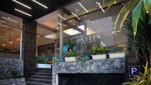 A modern hotel entrance with a glass facade, a stone wall, and a staircase leading to the lobby. - Daylin Guest House (Addis Ababa)