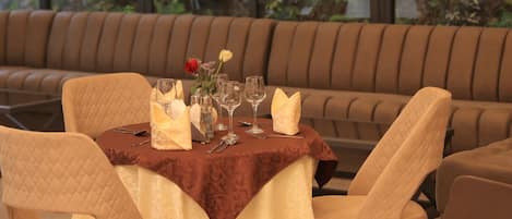 A dining area with a table set for four, a brown cushioned bench, and pendant lighting.