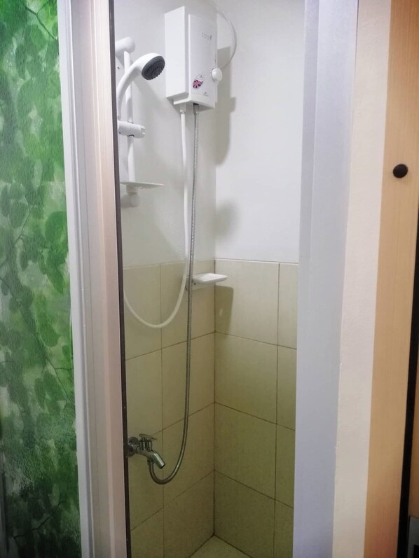 A small, enclosed shower area with a handheld showerhead and a wall-mounted control panel. - Trees Residence One Bedroom Unit (Quezon City)