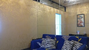 A room with a blue sofa with zebra print cushions, a small table with water bottles, and a framed artwork on the wall.