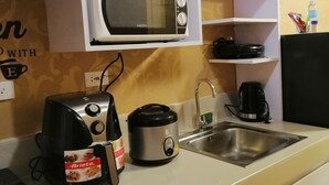 A compact kitchen with a microwave, toaster, and electric kettle.