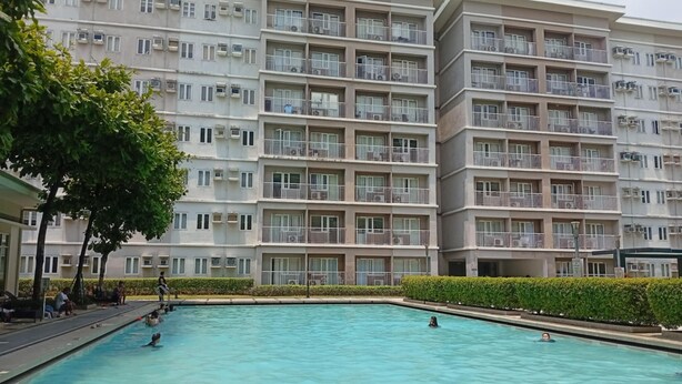A swimming pool area with a large building in the background.