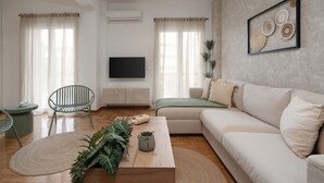 A modern living room with a sofa, a coffee table, a TV, and a wall-mounted artwork. - LIV - Seaside Getaway in Glyfada (Glyfada)