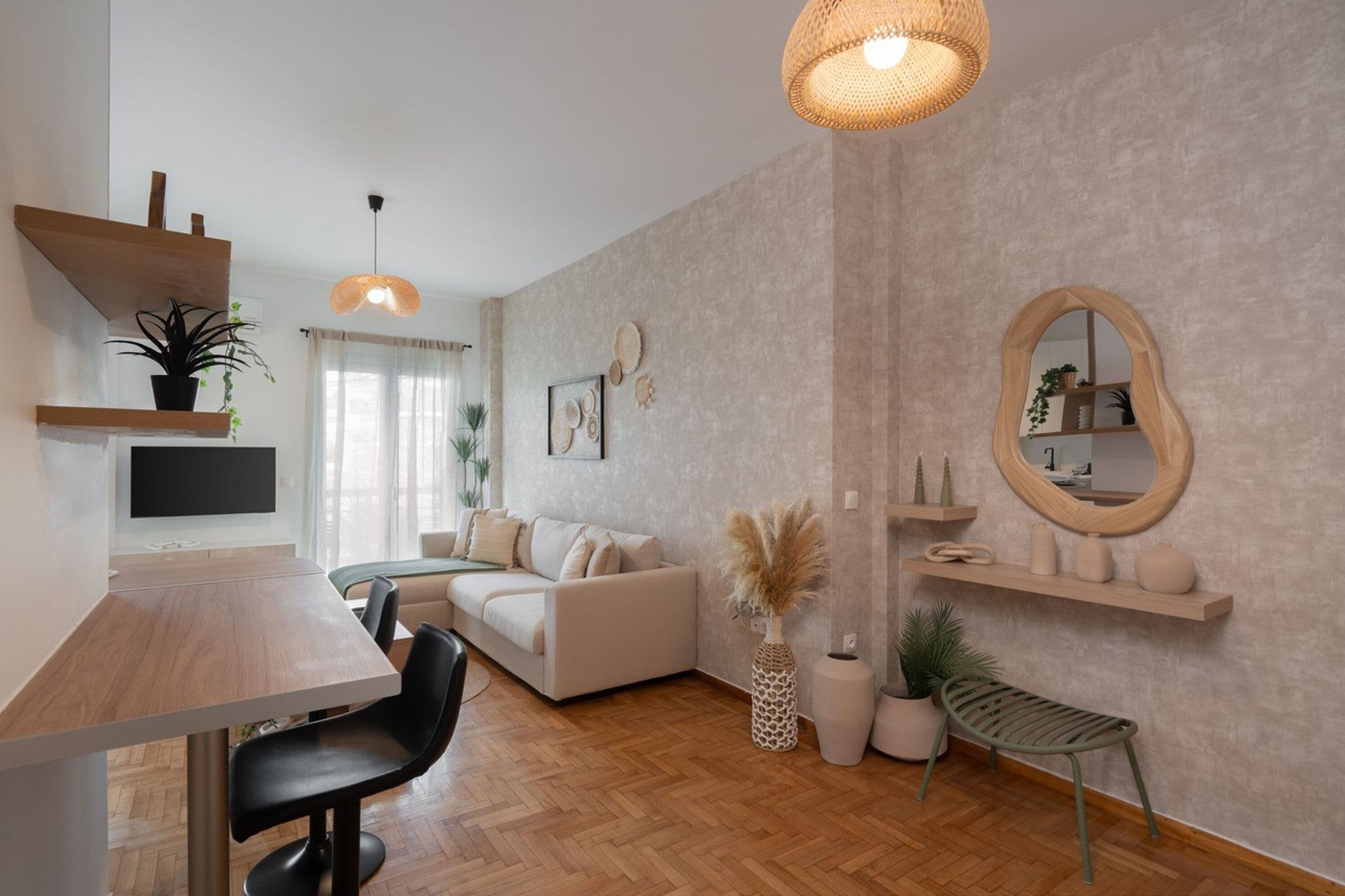 A modern living room with a wooden dining table, a sofa, a TV, and a hanging light fixture.