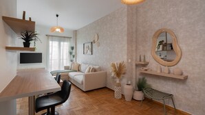 A modern living room with a wooden dining table, a sofa, a TV, and a hanging light fixture. - LIV - Seaside Getaway in Glyfada (Glyfada)