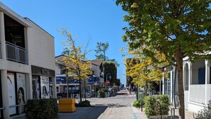 A cobblestone street lined with buildings, including a salon and a boutique. - Appartement au coeur dándernos les Bains (Andernos-les-Bains)