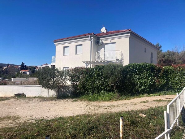 Um edifício de dois andares com telhado de telhas vermelhas, varanda e antena parabólica.