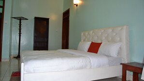 Une chambre à coucher avec un grand lit, une table de chevet, une lampe sur pied et une armoire.