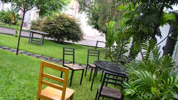 A garden patio with a wooden bench, a table, and chairs.