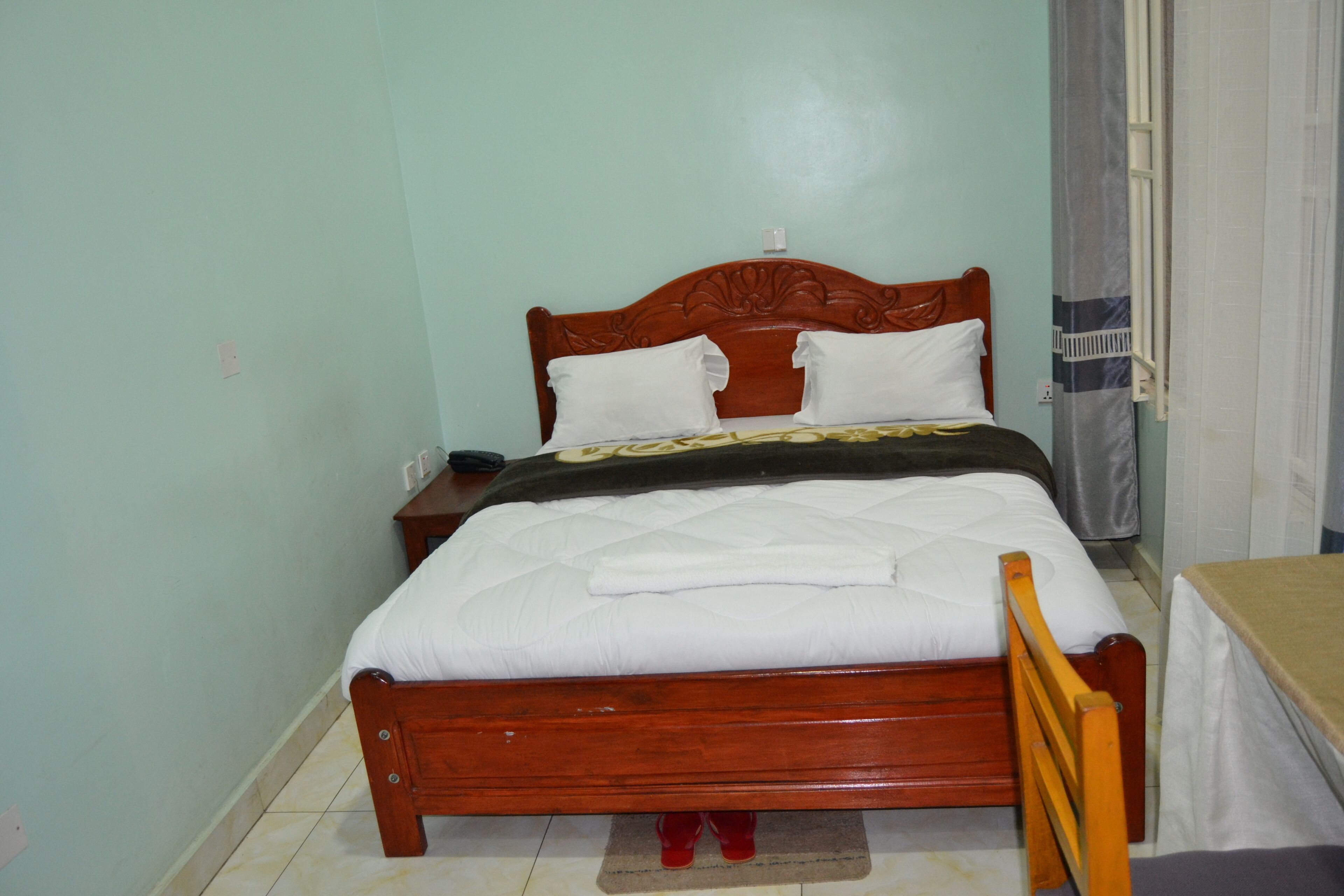 A single bed with a wooden frame, white bedding, and a small bedside table with a lamp.