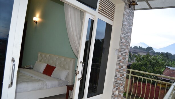 Une chambre à coucher avec un lit, une table de chevet, une fenêtre avec des rideaux et une vue sur les montagnes.
