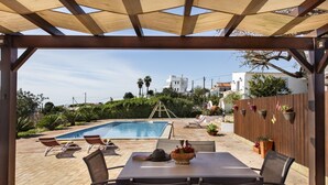 An outdoor pool area with lounge chairs and a table under a wooden pergola. - Quinta dos Medronheiros (Castro Marim)