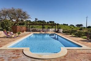 A rectangular swimming pool with a pergola and lounge chairs in the background. - Quinta dos Medronheiros (Castro Marim)