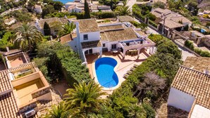 Zona residencial con piscina rodeada de exuberante vegetación y edificios de estilo mediterráneo.