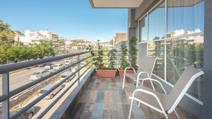 A balcony with a view of a cityscape, a railing, and potted plants.