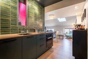 Una cocina moderna con una isla grande, horno empotrado y un comedor con mesa y sillas.