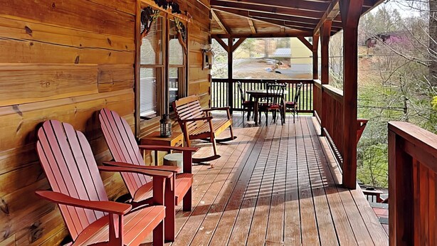 A wooden deck with Adirondack chairs and a table, overlooking a residential area.