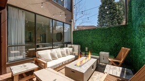 A modern outdoor living space with a sofa, chairs, a fire pit, and a green wall. - Updated Park City 2BR Sleeps 7-Natural Light & A/C-Walk to Park City Resort (Park City)