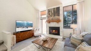 A modern living room with a fireplace, a television, a sofa, and a coffee table. - Updated Park City 2BR Sleeps 7-Natural Light & A/C-Walk to Park City Resort (Park City)