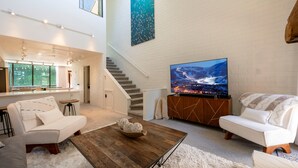 A modern living room with a large flat-screen TV, white sofas, a wooden coffee table, and a staircase leading to an upper level. - Updated Park City 2BR Sleeps 7-Natural Light & A/C-Walk to Park City Resort (Park City)