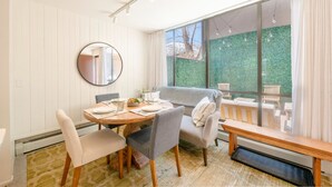A dining area with a round table, chairs, and a bench. There is a large window with a view of greenery outside. - Updated Park City 2BR Sleeps 7-Natural Light & A/C-Walk to Park City Resort (Park City)